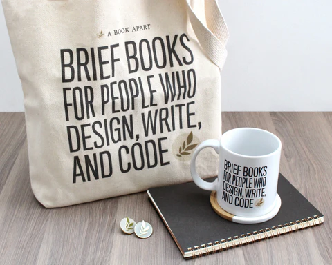 A Book Apart gear, including tote bag, mug, and pins
