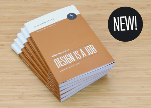 Stack of Design Is a Job 2nd Edition paperbacks on a light wood table.