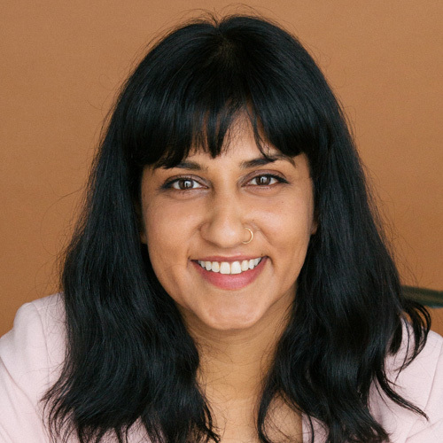 Portrait of  Sameera Kapila smiling in front of brown background.